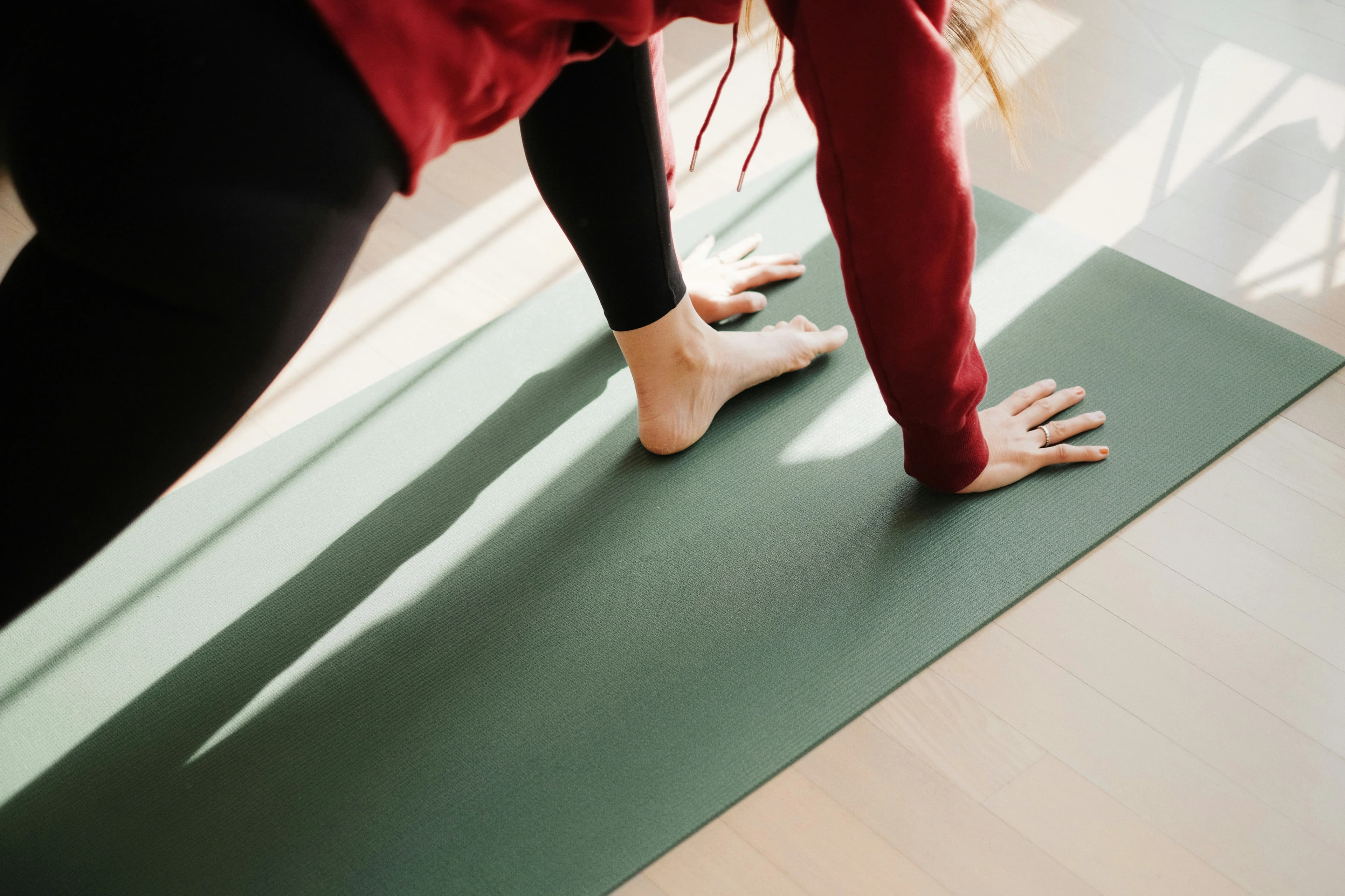 Rose Long sat leading a retreat class in cross-legged position on the floor, smiling with her eyes closed. She is sat in-front of a large bay window which looks out onto a large sun-filled garden. There is a large, golden gong to her left and a plant with a himilayan salt lamp on her right.
